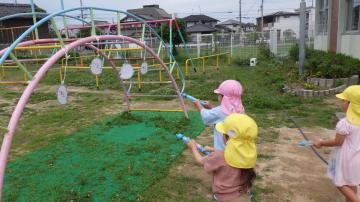 3、4歳児が水鉄砲で的を狙っている様子