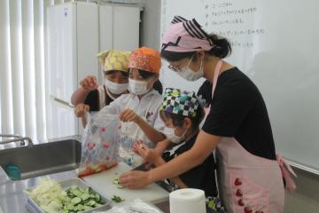 児童が公民館調理室で、キュウリを切ったり、それを袋に入れて浅漬けを作っている様子