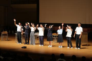 壇上で、生徒会による学校紹介の劇が行われる様子。生徒たちが横一列に整列しています。