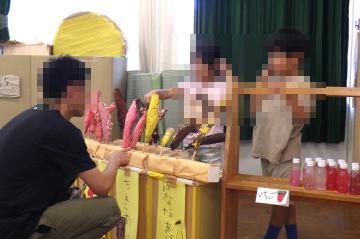 子ども園児が粘土で作ったチョコバナナを小学校教員が受け取っている様子