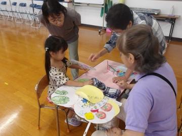 幼児が地域の方に昔遊びの道具づくりを教えてもらう様子