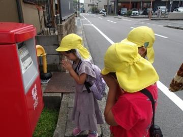 幼児がポストに無事にハガキが届けられることを願う様子