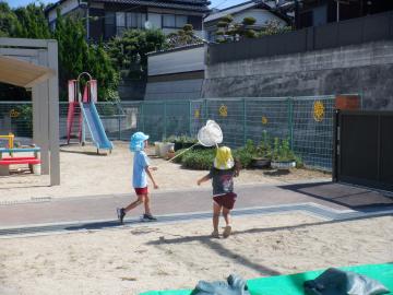 虫捕り網を使ってとんぼを捕まえようとしている二人の子供