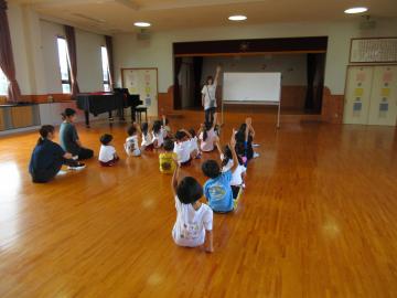 先生の話を座って聞き、挙手をする子供たち