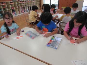 ハガキに祖父母の顔を描いている子供たち