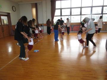 親子で手をつなぎ、大人の足の上に子供の足を乗せて歩く親子