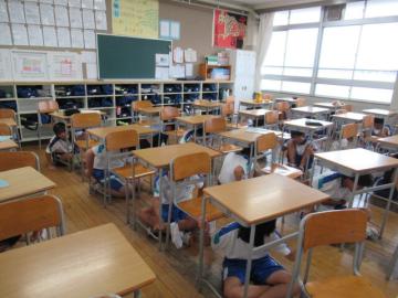 教室で生徒たちが机の下に身を寄せて避難訓練をしている様子