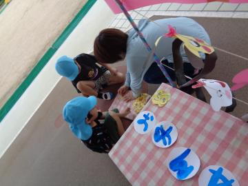 子どもたちと先生が紙や折り紙を使って一緒に作業している