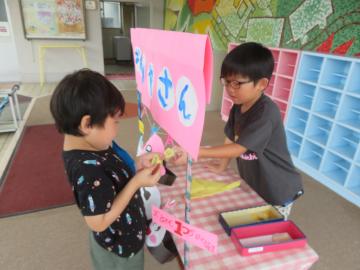 お面やさんと書かれた手作りの屋台を使って子ども2人がやり取りをしている
