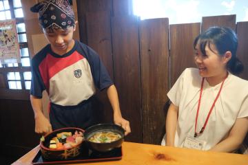 店員をしている生徒が料理をテーブルに運んでいる