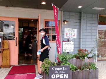 店の前でマスクを着けた生徒が立っている