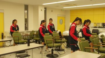 生徒が教室で椅子を並べたり整頓したりしている様子