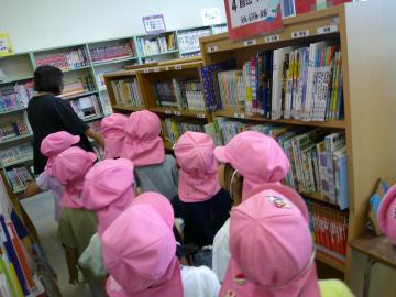 女性に図書室を案内をしてもらっている園児たちのようす