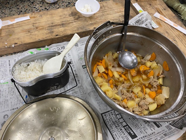 飯盒に入ったご飯と大きな鍋のなかの肉じゃがの写真