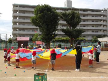4歳児がカラフルなパラバルーンをして遊んでいる様子