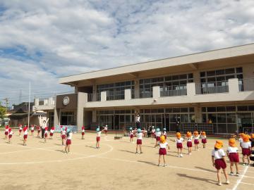 園庭で元気いっぱい体を動かして体操する子供たち