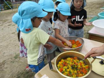 子供が黄色とオレンジのマリーゴールドを鍋に入れている様子
