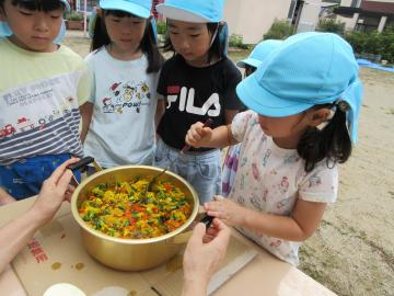 女の子が、鍋に入っている水とマリーゴールドをお玉でかき混ぜている様子