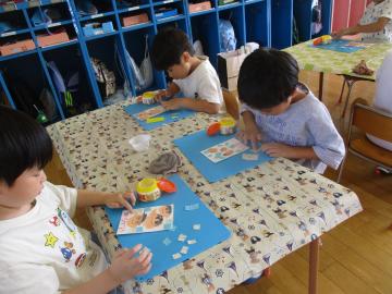 敬老の日に向けて、ハガキを作成し、折り紙を貼っている様子。
