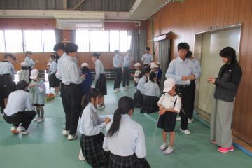 1年生と9年生がコマにひもを巻き付けている様子