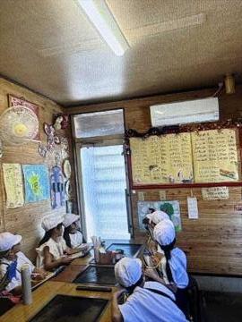 きんつばのお店の中を見学している様子です。どんなメニューがあるか、どのようなものを使って仕事をしているかなど説明を受けている様子です。