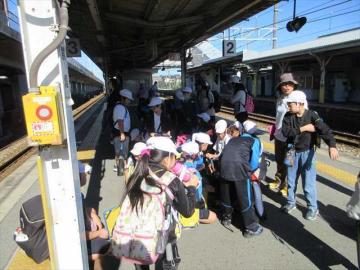 帽子とリュックの子どもたちが駅のホームで集合している風景