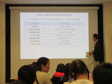 会議室で資料が映された壁を座って見ている児童たち