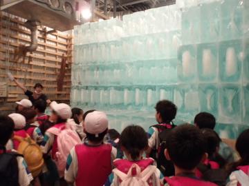 子どもたちが、透明な氷のブロックを貯蔵している室内を見学する様子