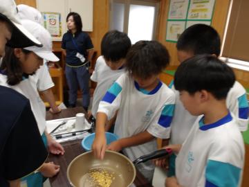屋内で児童たちが鍋を囲んでポップコーンを作っている様子