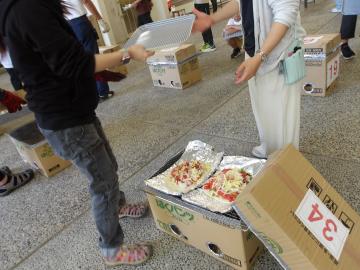 屋外でピザを焼く段ボール窯を使う児童たちの様子