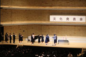 講堂の舞台で数人が並びピアノ近くで表彰を受ける文化発表会の様子