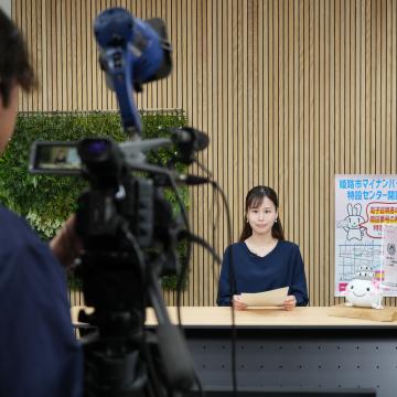 スタジオでカメラの前でキャスター収録をする推進員