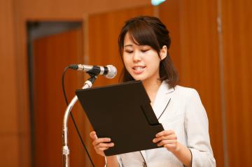 壇上でマイクの前に立ち司会をする推進員